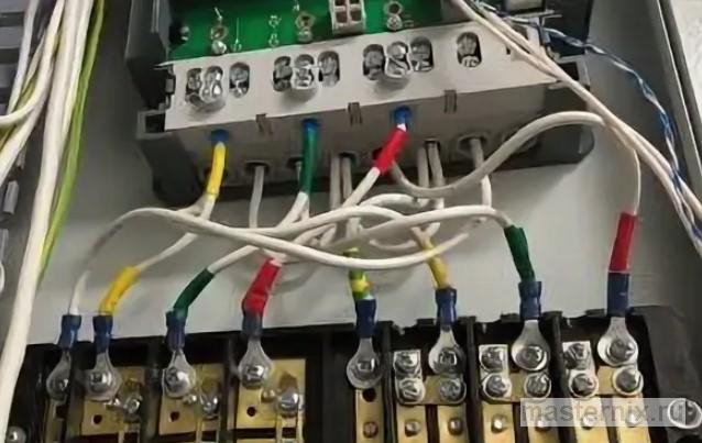 Монтажник затягивает клеммы трехфазного ограничителя перенапряжения в распределительном шкафу