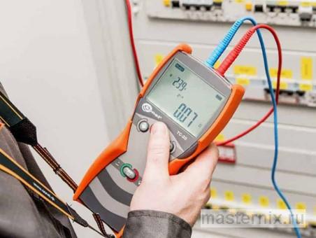 Специалист электролаборатории проверяет параметры петли фаза-ноль с помощью поверенного измерительного прибора